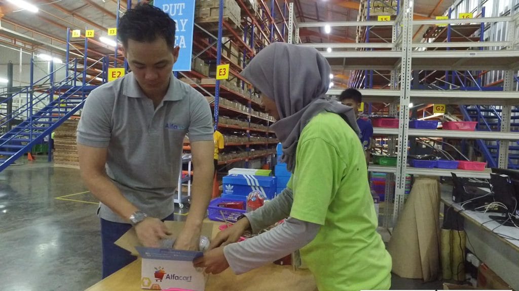 Dalam rangka Hari Pelanggan Nasional, Haryo Suryo Putro (Chief Marketing Officer dan Chief Operational Officer Alfacart.com, kiri), melakukan pengepakan barang untuk pelanggan Alfacart.com.