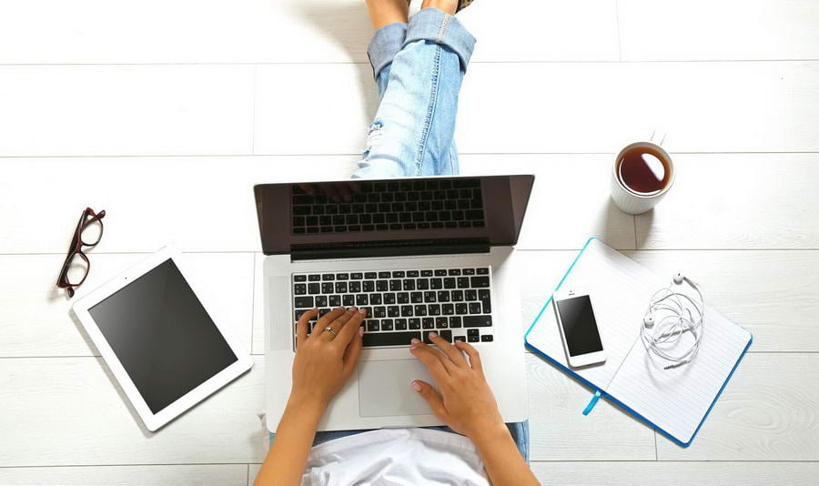 Top view of young woman sitting on floor with laptop